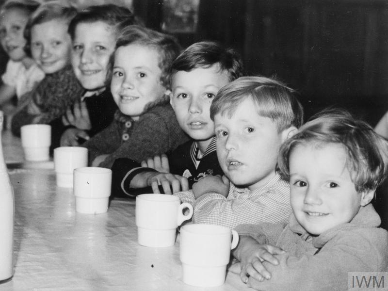 Belgian refugee children waiting for their afternoon tea in London during 1940. Imperial War Museum.