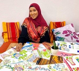 Hafza surrounded by artwork created at one of her workshops